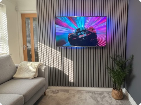 TV wall mounted on slat panel feature wall with ambient lighting